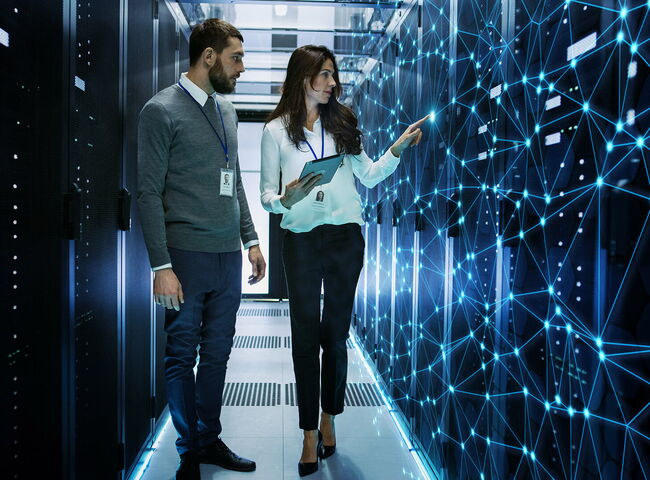 2 Menschen betrachten eine digitale Karte in einem Serverraum